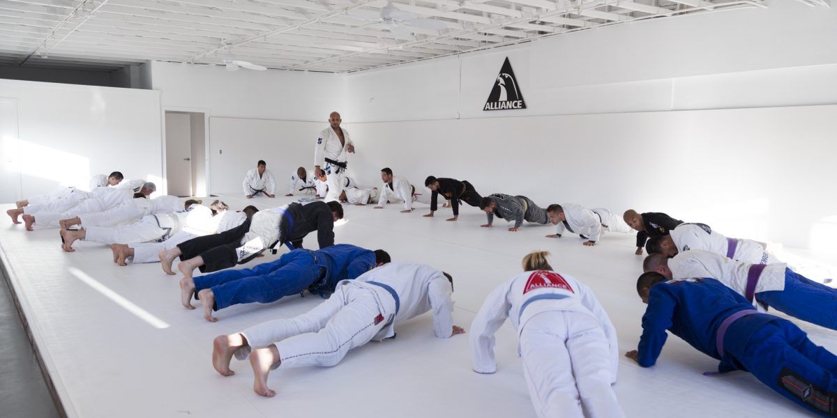 A Class Doing Push Ups on the Floor in a room with white interiors